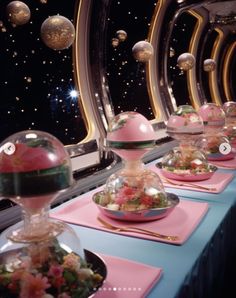 a long table topped with plates and bowls filled with different types of food on top of pink place mats