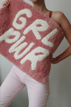 a woman holding up a pink rug with the words pop punk on it in white letters