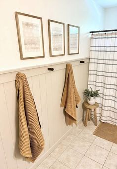 two towels hanging on the wall next to a bench and stool in a room with white walls