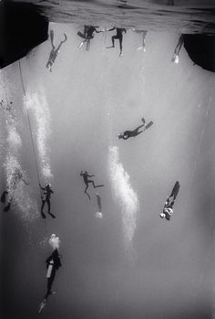 several people are swimming in the water with their surfboards under an underwater tunnel that looks like a waterfall