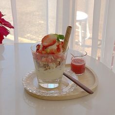 a bowl of fruit and yogurt on a plate with a glass of juice