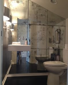 a white toilet sitting next to a sink in a bathroom under a large mirrored wall