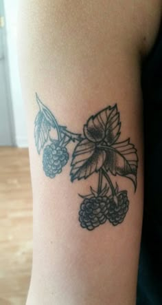 a tattoo with berries and leaves on the arm