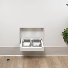 an empty dishwasher sitting on the floor next to a potted plant