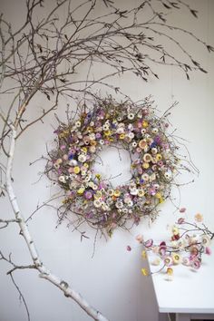 a wreath is hanging on the wall next to a branch with flowers and branches around it