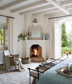 a bedroom with a fireplace in the middle and lots of curtains on the window sill