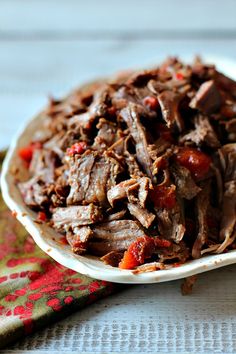 a white bowl filled with shredded meat on top of a table