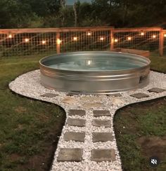 a hot tub sitting in the middle of a yard next to a fence with lights on it