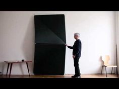 a man standing in front of a black refrigerator