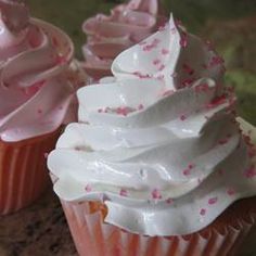 three cupcakes with white frosting and pink sprinkles on them