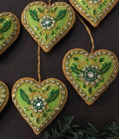 four green heart shaped ornaments hanging from a christmas tree with beaded trimmings