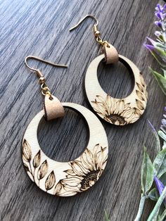 a pair of wooden earrings with sunflowers on them