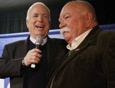 two older men standing next to each other holding microphones in their hands and laughing