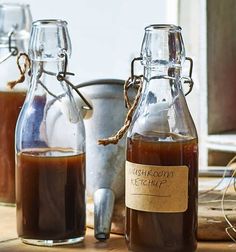 three glass bottles filled with liquid sitting on top of a wooden table next to metal buckets