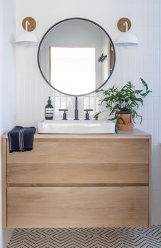 a bathroom with a sink, mirror and potted plant on the counter in front of it