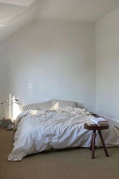 a bed sitting in the middle of a bedroom under a slanted ceiling next to a window