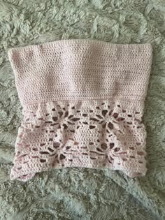 a pink crocheted blanket laying on top of a bed