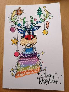 a christmas card with a reindeer wearing a sweater and ornaments on it's head