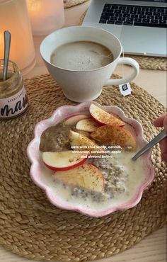 a bowl of oatmeal with apples and cinnamon in front of a laptop