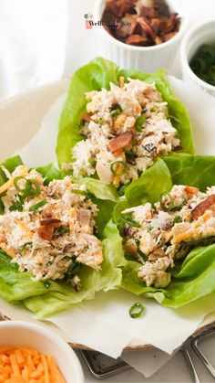 three lettuce wraps filled with chicken salad on top of a white plate next to carrots