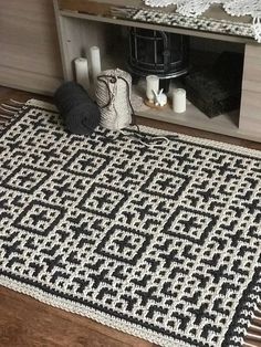 a black and white rug sitting on top of a wooden floor next to a shelf