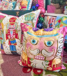 two decorative pillows sitting on top of a rug next to each other in front of a christmas tree