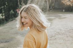 a woman with blonde hair is smiling at something in the distance while holding a frisbee