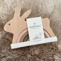 a wooden bunny toy sitting on top of a fluffy rug next to a package of stickers