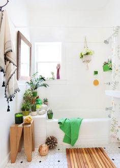 a white bathroom with plants and towels on the bathtub