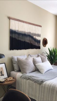 a bedroom with a bed, table and chair in front of the wall hanging on the wall