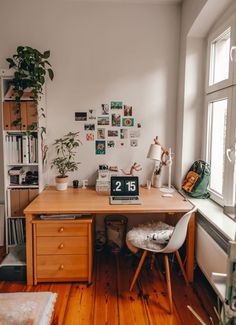 a wooden desk sitting next to a window in a room with lots of pictures on the wall