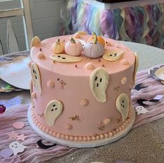 a pink cake with ghost decorations on it