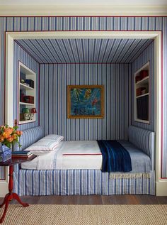 a bedroom with blue and white striped wallpaper, a painting on the wall and a bed