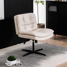 a white chair sitting on top of a wooden floor next to a potted plant