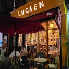 people sitting at tables in front of a restaurant