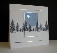 a white card with trees and a star in the middle, on top of a table