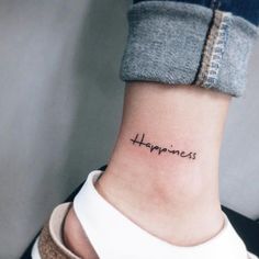 a woman's ankle with the word happiness tattooed on her left side ribcage