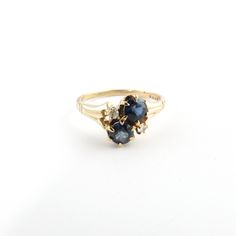 a gold ring with two blue stones on it's sides, sitting on a white surface