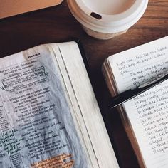 an open book sitting on top of a wooden table next to a cup of coffee