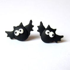 two black bats with googly eyes are on a white surface, one is larger than the other