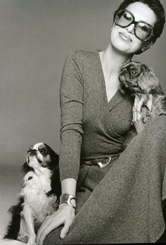 a black and white photo of a woman sitting with two dogs in front of her