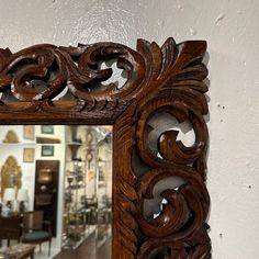 an ornate wooden mirror hanging on the wall