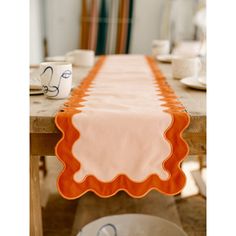 an orange and white table runner sitting on top of a wooden table