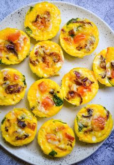 several small muffins on a plate with cheese and vegetables in the middle, ready to be eaten