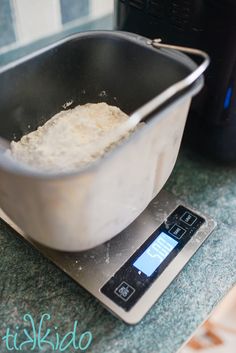 a large metal bowl sitting on top of a scale next to a black blender