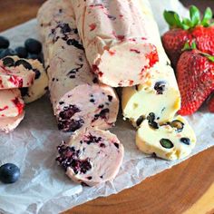 some fruit and ice cream are on a paper towel next to strawberries, blueberries, and raspberries