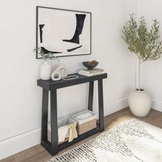 there is a black table in the corner with a plant on it and a white vase next to it