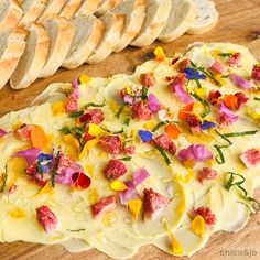 a wooden table topped with slices of bread and colorful flowers on top of it's crust