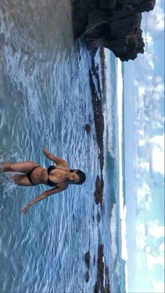 a woman is swimming in the ocean next to rocks