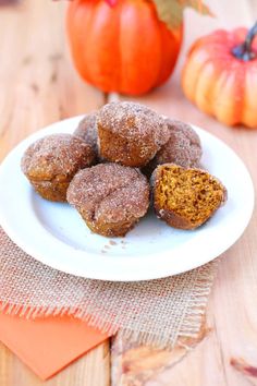 a white plate topped with donuts covered in powdered sugar next to pumpkins